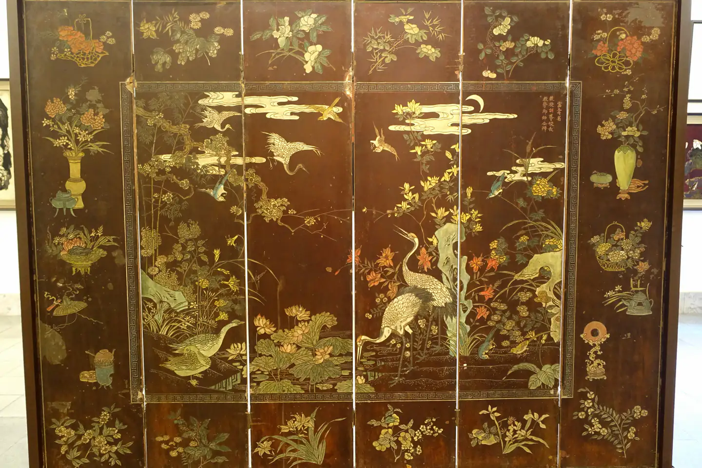 Một bức bình phong sơn mài nhiều tấm thời Nguyễn trưng bày trong bảo tàng. Trên nền sơn nâu sẫm là hạc, vịt, chim bay, hoa sen, cúc và mây trăng, xung quanh là viền hoa lá và các bình hoa, giỏ hoa nhỏ.